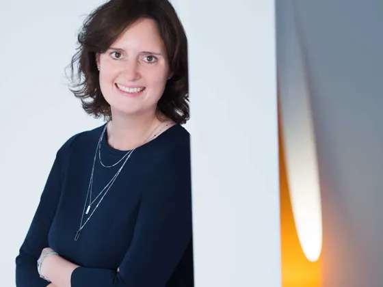 Porträt von Sandra Weiß in dunklem Oberteil an einer hellen Wand